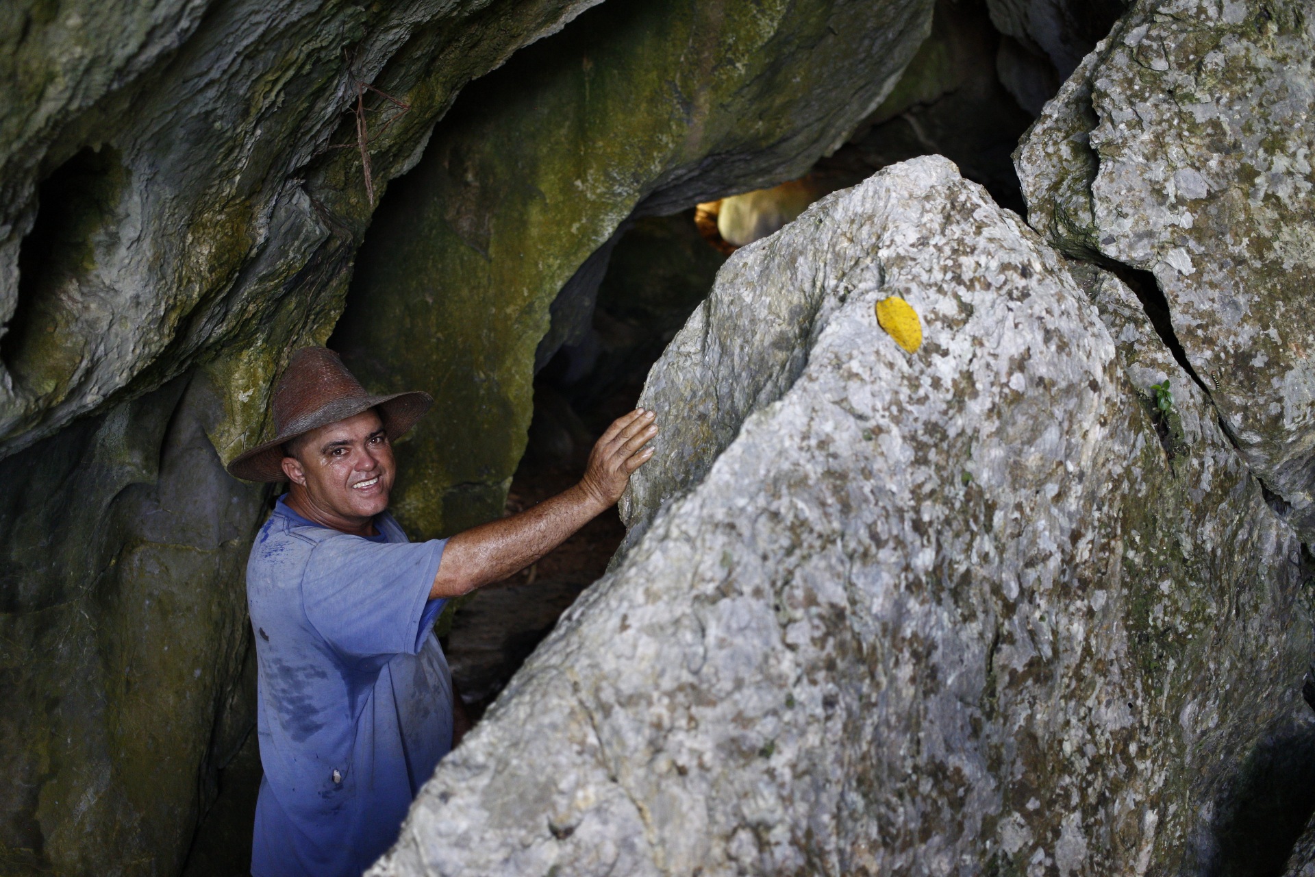Mann mit Hut berührt eine große Felswand in einer Höhle