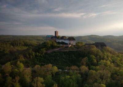 Wartburg bei Eisenach auf dem bewaldeten Berg, Drohnenaufnahme im Abendlicht