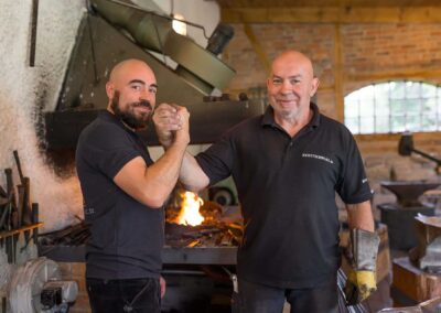 Zwei Schmiede in Arbeitskleidung in ihrer Werkstatt im Ilmtal