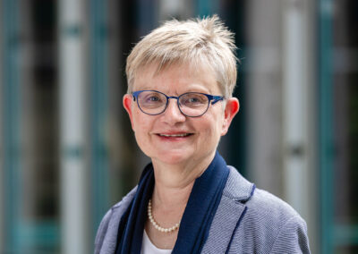 Business-Porträt einer Frau mit Brille und Blazer vor Glasfassade