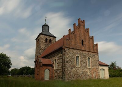 Alte Backsteinkirche mit Turm vor dramatischem Wolkenhimmel