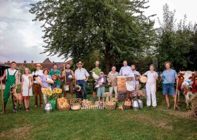 Gruppe von Menschen steht mit Gemüse und Tieren auf einer Wiese