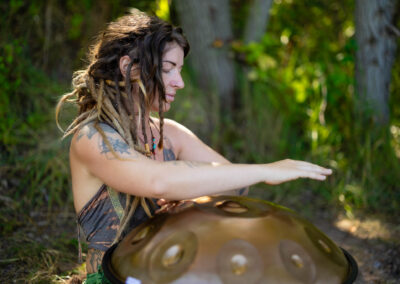 Frau mit Dreadlocks spielt Handpan im Wald