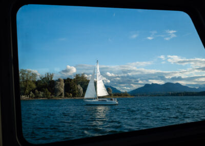 Segelboot auf einem See, gesehen durch ein abgerundetes Fenster
